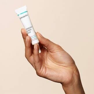 Hand holding a small tube of skincare product